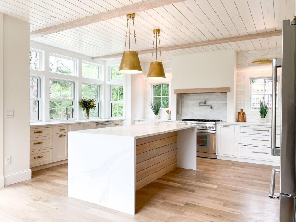 Open-concept kitchen with marble island and shiplap ceiling inside a custom home by Oak in Hull, MA.