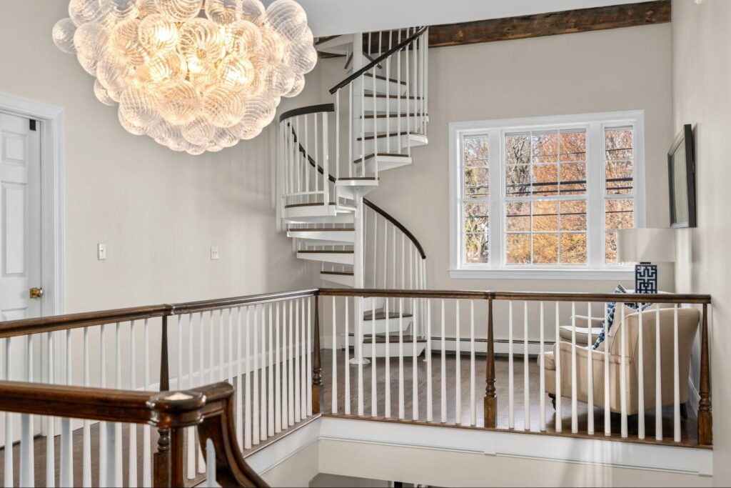 Spiral staircase and statement lighting inside a Duxbury custom home built by Oak's design-build team