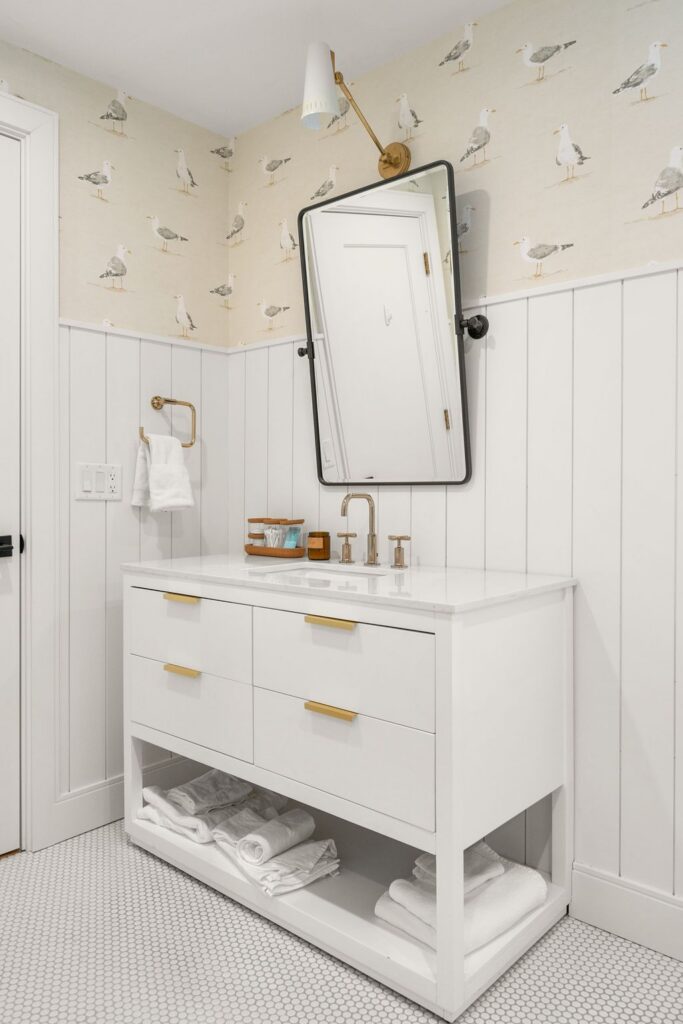 Custom bathroom with seagull wallpaper, vertical shiplap, and brass fixtures in a Scituate, MA custom home by Oak's design-build team.